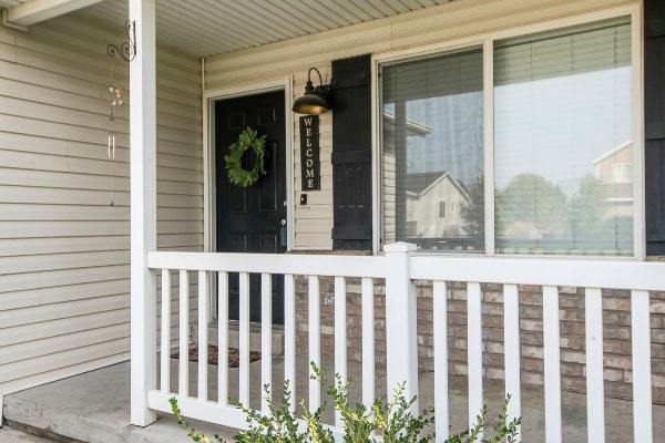 Porch and black front door on home with vinyl siding